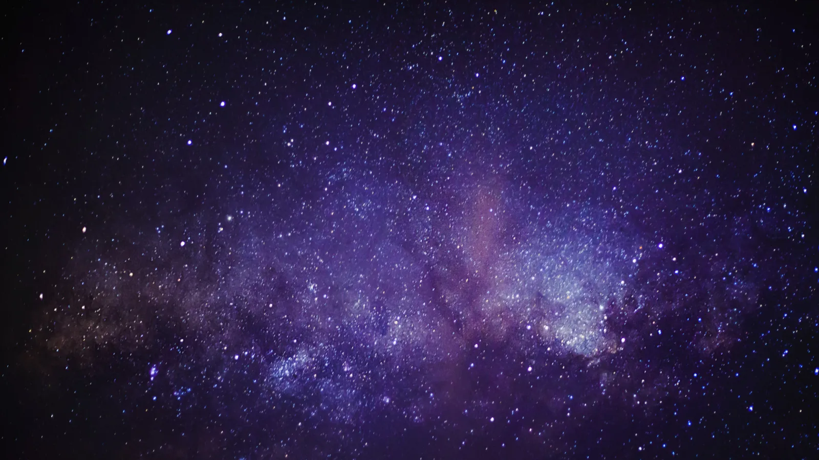 A glowing blue/purple gaseous nebula seen against a black sky filled with stars