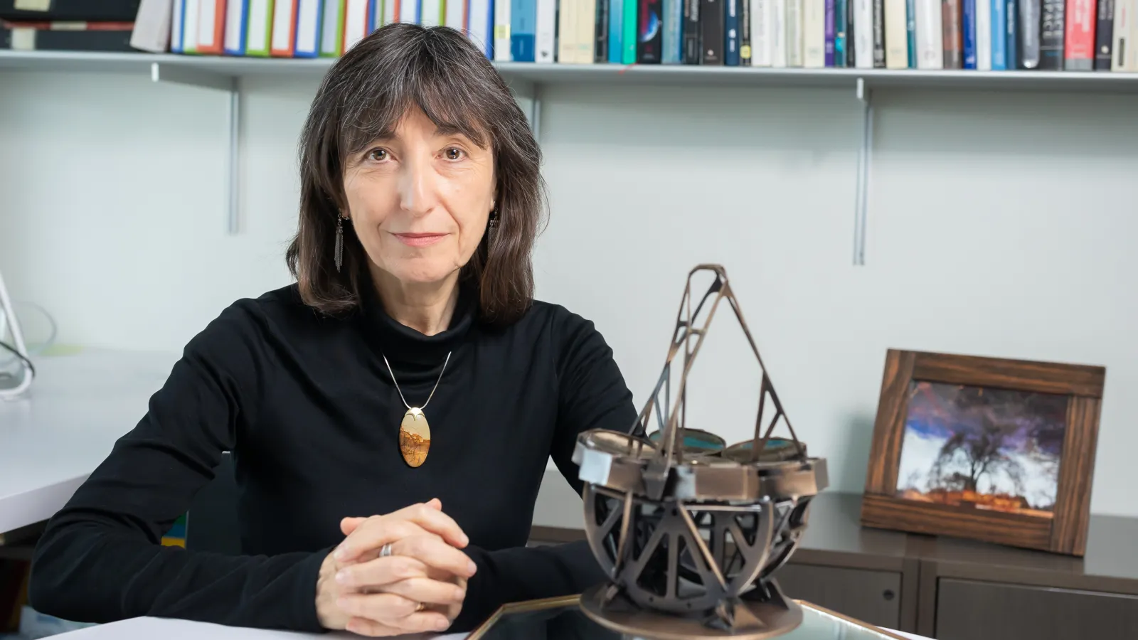Professor Wendy Freedman sitting at a table with a model of the Giant Magellan Telescope in front of her