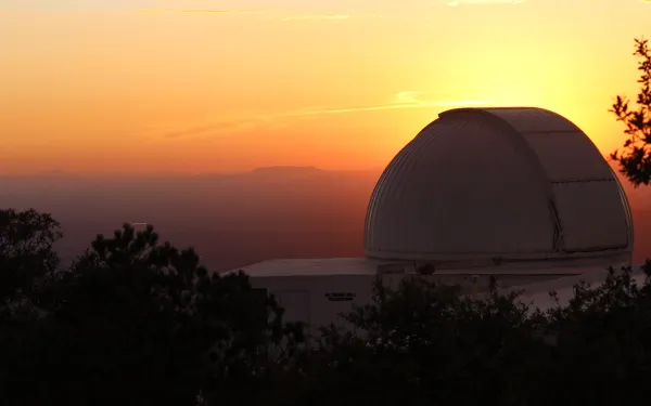 Observatory domes at the MDM observatory backlit by a colorful sunset, a photo my Nikki Justice