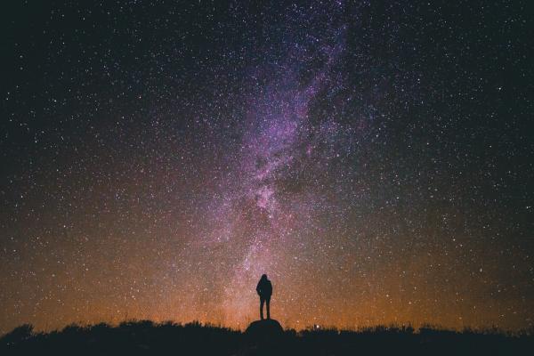 Man standing in front of the Milky Way at night. Credit: Greg Rakozy on Unsplash