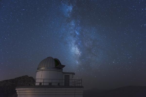 Picture of an observatory at night with the milky way going across the sky