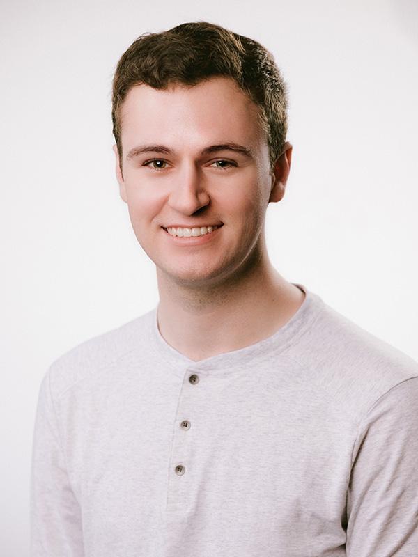 A smiling man wering a light gray tee-shirt